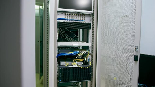 a bunch of patch network cables sorted in a rack cabinet leading from a patch panel in a server rack in a data center room internet cloud storage