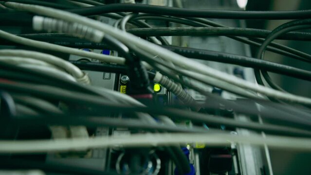 close-up of a pile of network patch cables sorted in a rack cabinet leading from a patch panel in a server rack in a data center room
