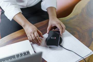 Fototapeta premium Charging mobile phone battery with wireless charging device in the table. Smartphone charging on a charging pad. Mobile phone near wireless charger Modern lifestyle technology concept
