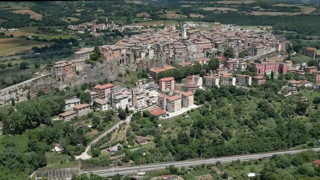 The hilltop town of Orte, Italy is shown from an aerial view during the day. This area has been inhabited since the 6th century BC, and the town was built on a high tuff cliff.