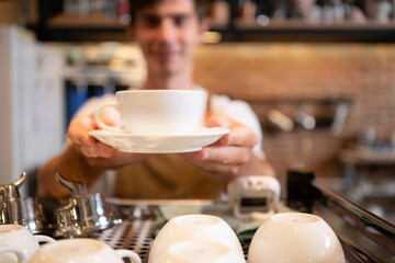 Portrait of a smiling male barista holding a cup of coffee