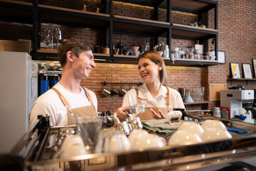 Barista working in cafe. Portrait of young male barista standing behind counter in coffee shop.