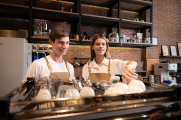Barista working in cafe. Portrait of young male barista standing behind counter in coffee shop.