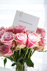 Bouquet of beautiful pink roses with a greeting card, clsoe-up. Top view.