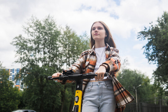 young woman on an electric scooter rides down the street