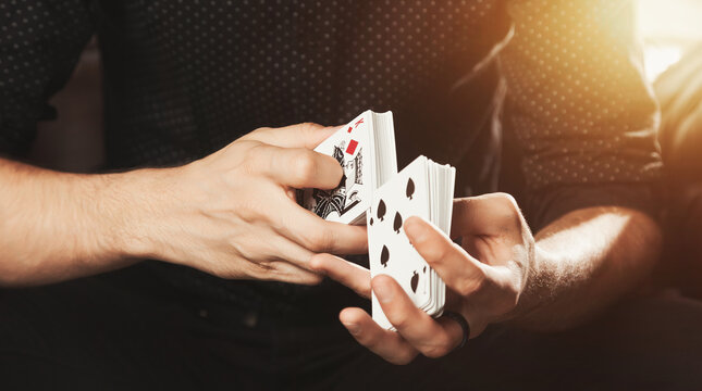 Close up of gambler guy hands of magician shuffling gambling cards. Man clever showing performing playing cards. Concept of magic, casino, performance, circus, gambling, game, show. Copy ad text space
