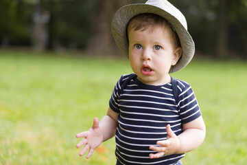 Portrait of a cute baby boy in hat and striped shirt outdoors