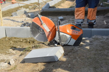 A concrete block lies next to a circular saw on a construction site.