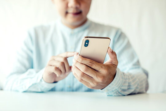 Cheerful businessmen use smartphones while sitting on the sofa at home. Handsome young asia man sitting on a couch reading messages on a mobile phone.