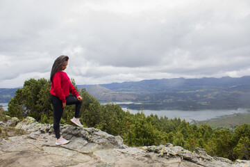 lonely woman on a mountain looking at the landscape and a lake