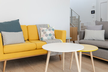 Bright and minimalist living room with gray and yellow armchairs, comfortable cushions, gray...