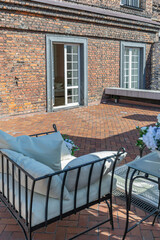 a chic terrace of a country house with wrought iron furniture, vases with flowers and columns on a bright summer sunny day