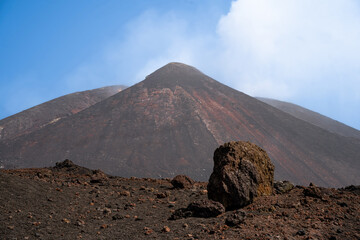 The view of the Etna volcano peak with blue sky and some steam coming fromt he crater. 