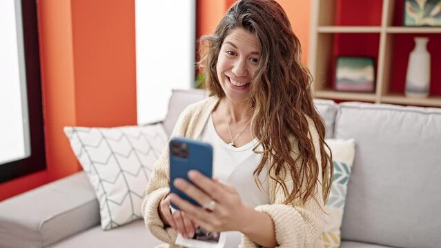 Young pregnant woman having video call showing baby ultrasound at home