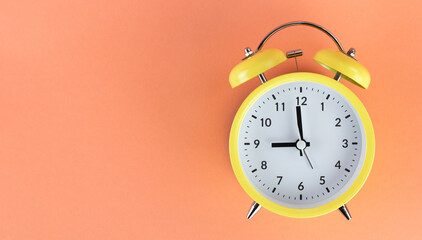 Banner yellow alarm clock on a colored orange background. Minimalism. Concept of time, planning. Top view. Copy space.