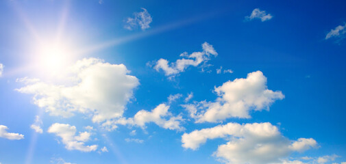 Bright sun, blue sky and light clouds. Wide photo.