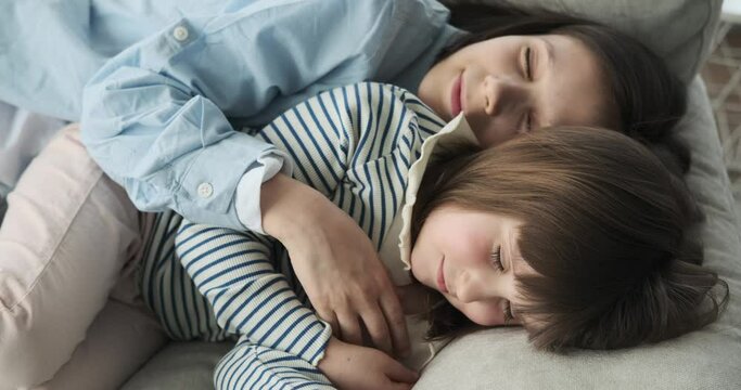 Sibling in the cozy living room, a brother and sister find tranquility on the soft couch. Their eyes closed, they peacefully drift into a world of dreams, completely at ease in each other's presence.