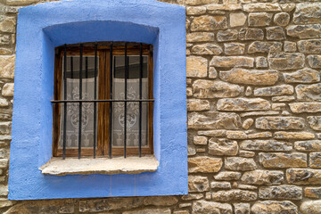 Fototapeta na wymiar Window with a blue painted frame, in a rural house in an old town.