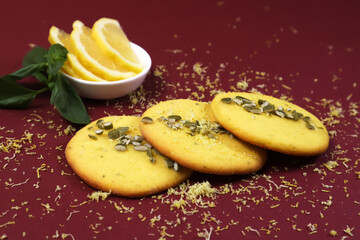 Fragrant yellow lemon cookies with pumpkin seeds on a burgundy table. Shallow depth of field
