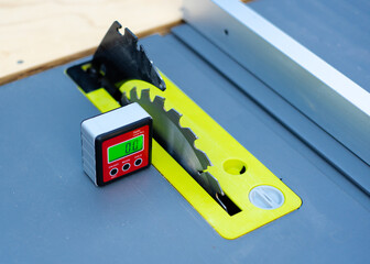 Digital level box inclinometer showing level 0-degree angle with magnetic base attaches to metal surface of brand-new table saw