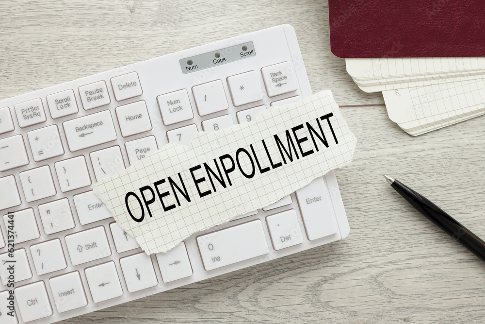 Poster open enrollment. text on torn paper on white keyboard