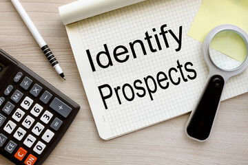 Identify Prospects top view of an open notebook with text. magnifying glass on notepad page.close-up