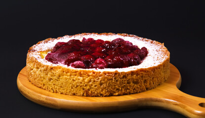 Pie with raspberry jam and powder on a wooden board. Close-up