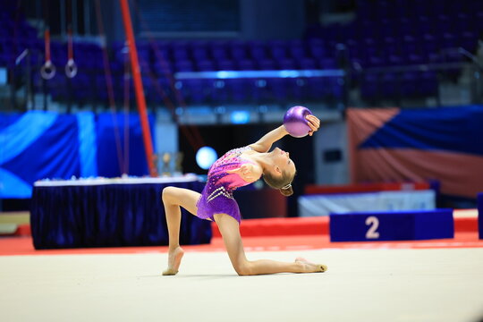 girl gymnast performs an exercise with a ball