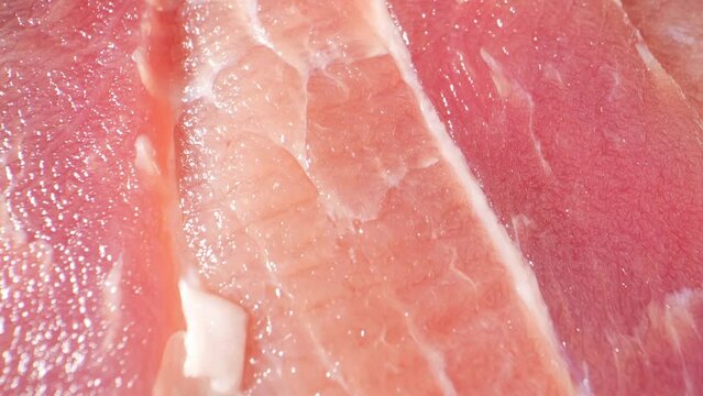 Macro video of raw pork belly slice with a probe lens reveals intricate marbling, tender texture, and juicy fat, tantalizing the senses. Meat industry. Frozen meat concept. Food background. 4K UHD
