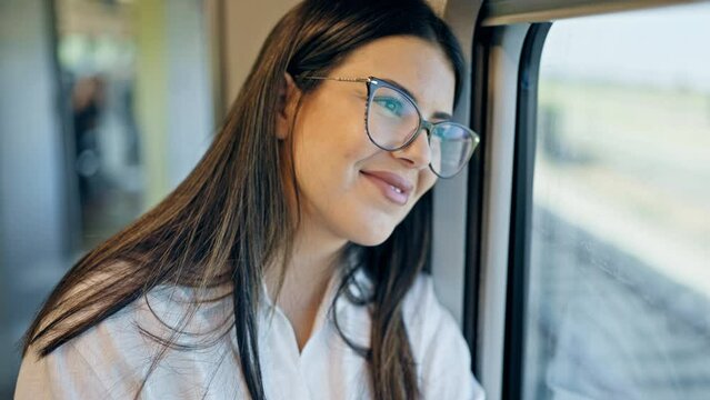Young beautiful hispanic woman smiling happy looking through the window at train station