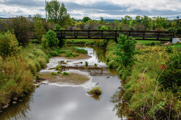 Fototapeta na wymiar A Metal Bridge Across The River At The Local Park