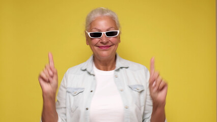 An elderly woman points her finger to attract attention on a beige background