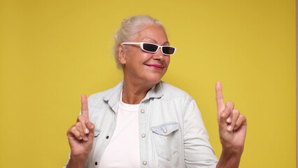 Elderly European woman in sunglasses is dancing