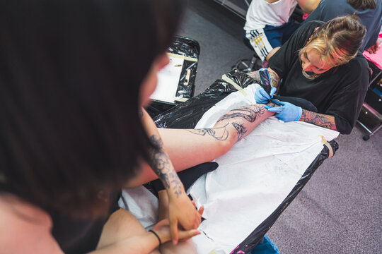 high angle view of a tattooist girl making a new tattoo on a girl's leg. High quality photo