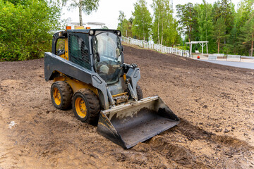  A loader with a bucket clears the site for construction