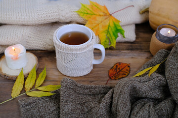 autumn flatlay in style Scandinavian hugg with tea in mugwarm woolen clothes, yellow leaves on wooden table, candle is burning, concept of tea party, good weather, cozy autumn mood