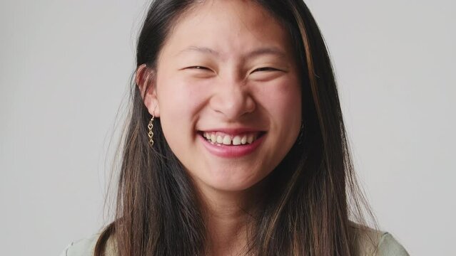Close up, young woman looking at camera and laughing isolated over white background in studio