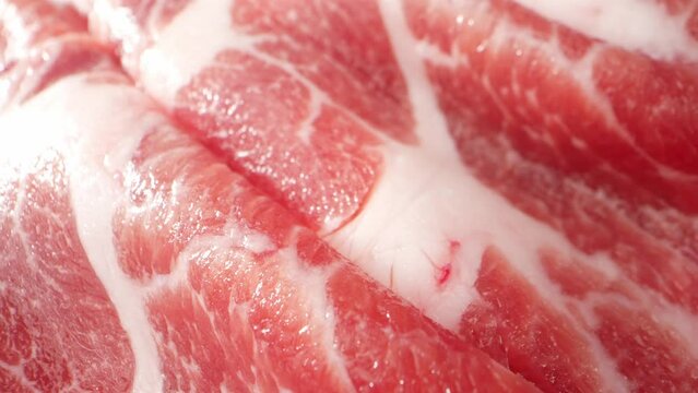 Macro video captures the intricate details of raw pork neck slices, showcasing the marbling and textures with stunning clarity. reveals a visually captivating exploration of this delicious cut. 4K
