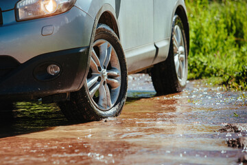 Car wheel standing offroad in a mountain creek close-up view