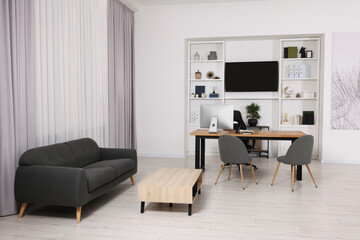 Stylish director's workplace with comfortable furniture and tv zone in room. Interior design