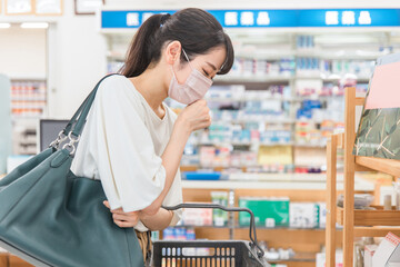 薬局・ドラッグストアで買い物をする体調不良・咳をするマスク姿の女性
