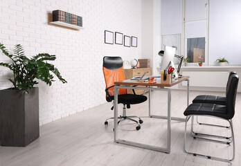 Stylish director's workplace with comfortable desk, computer and chairs for visitors in office. Interior design