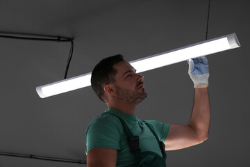 Ceiling light. Electrician installing led linear lamp indoors