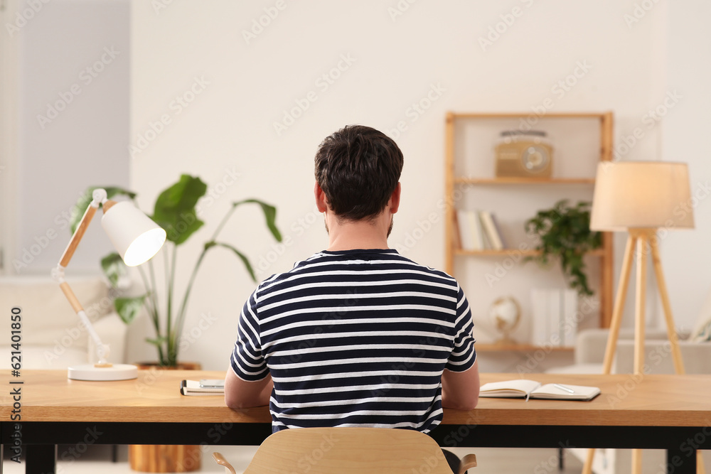 Poster Home workplace. Man working at wooden desk in room, back view