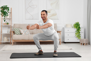 Fototapeta na wymiar Man doing morning exercise on fitness mat at home