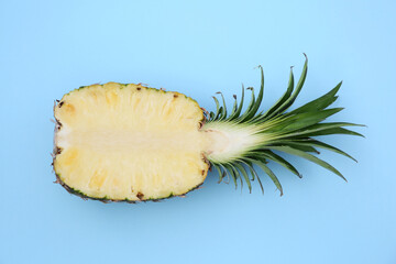 Half of ripe pineapple on light blue background, top view