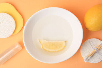 Lemon face cleanser. Fresh citrus fruits and personal care products on pale orange background, flat lay