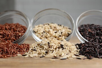 Different types of rice on wooden table, closeup