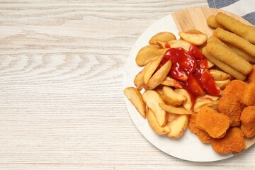 Different snacks with tasty ketchup on wooden table, flat lay. Space for text