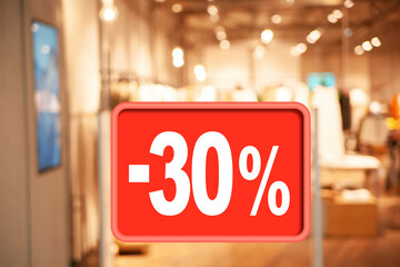 Sale sign and blurred view of fashion store with clothes